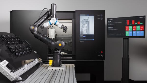 A sleek robotic arm mounted in front of an open-doored matte-black machine displaying an X-ray of an automotive part on an inset touchscreen prepares to reach for a shelf of similar parts to scan. A nearby graphical analysis dashboard displays quality control results from the past six scanned parts.